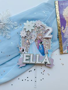 two frozen princess birthday party decorations and a book on a table with confetti