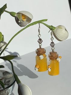 two glass jars filled with honey sitting on top of a table next to a flower