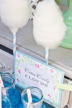 cotton candy clouds are sitting on top of jars with blue liquid in them and a sign that says cotton candy clouds