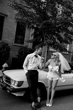 a man and woman standing next to a car