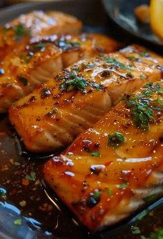 grilled salmon fillets on a plate with lemon wedges and parsley garnish