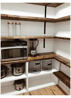 a kitchen area with shelves, pots and pans on the shelf next to an open microwave oven