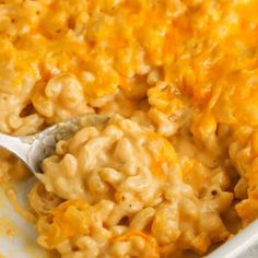 a spoon full of macaroni and cheese in a casserole dish