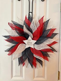 a red, white and black mesh wreath hanging on a door