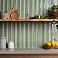 a kitchen with green striped wallpaper and wooden shelves filled with pots, lemons and other items