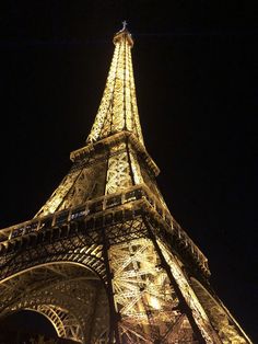 the eiffel tower lit up at night with lights on it's sides