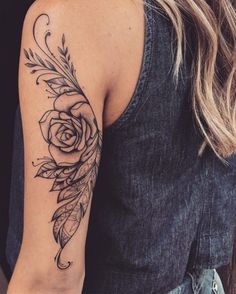 a woman's arm with a rose and feathers tattoo on the left side of her arm