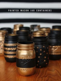 painted mason jar containers sitting on top of a wooden table