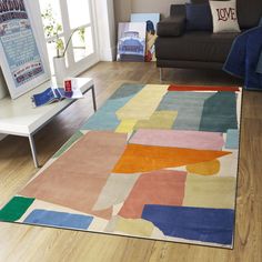 a living room with a large rug on the floor and a couch in the background