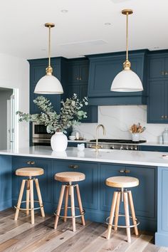 a kitchen with blue cabinets and stools in the center, two lights hanging over the island