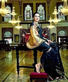 a woman sitting on top of a wooden table in a room with chandeliers