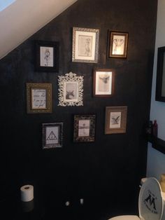 a bathroom with black walls and pictures on the wall