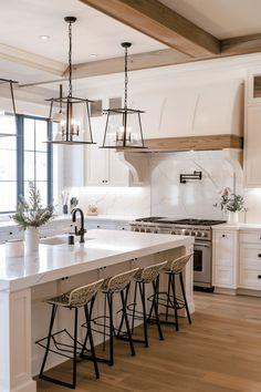 a kitchen island with stools and lights hanging from it's ceiling over the sink