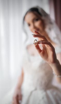 a woman in a wedding dress holding a ring