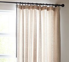 the curtain is hanging in front of a window with white walls and windowsills