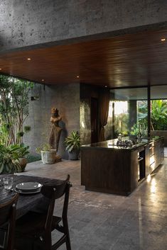 an open kitchen and dining room area in a modern home with large windows overlooking the jungle