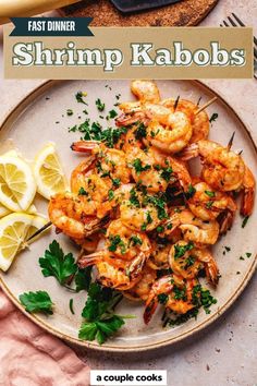 shrimp kabobs on a plate with lemons and parsley