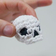 a hand holding a tiny crocheted object in the shape of a dog's head