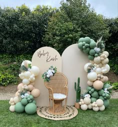 an outdoor area decorated with balloons, greenery and a wicker chair in front of a sign that says baby kohl