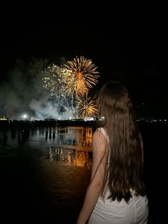 a woman looking at fireworks on the water