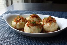 some food is in a white bowl on a blue place mat with a window behind it