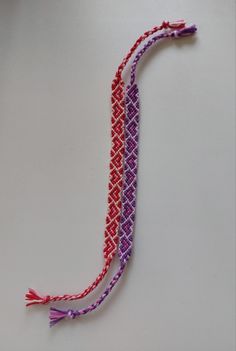 two pieces of colorful string with tassels on white surface