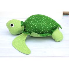 a green stuffed turtle sitting on top of a white table