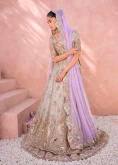 a woman in a purple and gold lehenga standing next to some stone steps