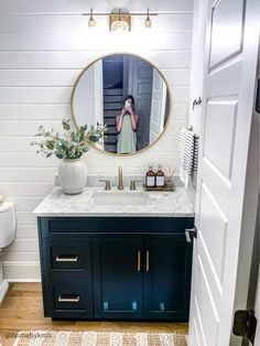 a bathroom with a sink, mirror and toilet in the corner next to a wooden floor