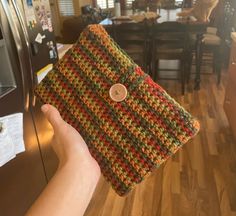 a hand holding up a crocheted purse in front of a kitchen counter top