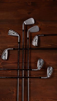 four different types of golf irons on a wooden surface