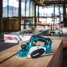 a blue and white electric sander sitting on top of a wooden table in a building