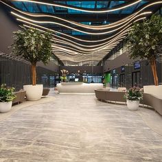 an empty lobby with couches and potted trees in the center, surrounded by lights