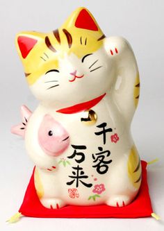 a ceramic cat figurine with chinese writing on it's chest holding a pig