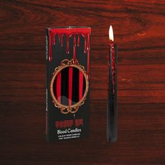 a red and black candle next to a box with blood dripping down the sides on a wooden table