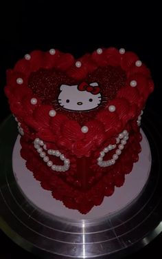 a hello kitty heart cake with pearls on the bottom and red icing in the middle