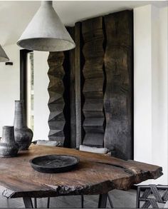 a wooden table with two vases on top of it and some lights hanging from the ceiling