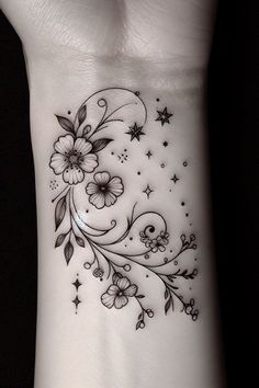 a wrist tattoo with flowers and stars on the side of it, in black and white