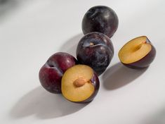 plums and peaches on a white surface