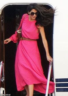 a woman in a pink dress stepping out of an airplane