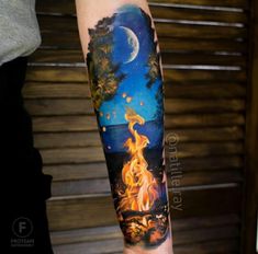 a person with a tattoo on their arm that has a fire in the forest and moon above it