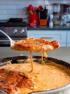 a person is lifting some food out of a skillet with a spatula in it