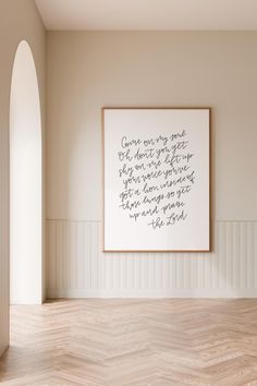 an empty room with a framed quote on the wall and wood flooring in front of it