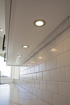 the lights are on above the counter in the kitchen area, while the tile is white