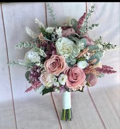 a bridal bouquet with pink roses, white and green foliage on a wooden background