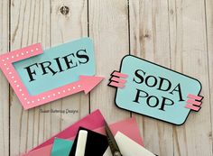 two pieces of paper cut out to look like they are advertising soda pop and fries