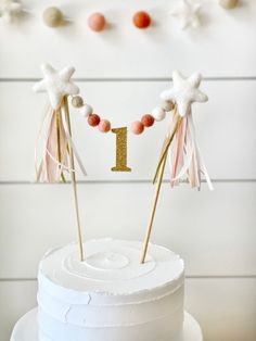 a white cake with pink and gold decorations on it's top is one year old