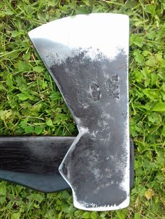 a large knife laying on top of green grass next to a black blade with holes in it