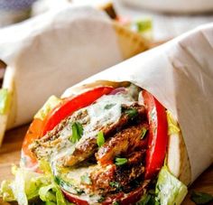 a sandwich with lettuce and tomatoes on it sitting on top of a cutting board