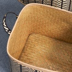 two woven baskets sitting next to each other on top of a blue carpeted floor